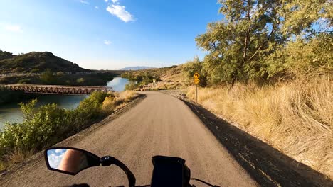 riding a bicycle along a trail and over a bridge over a river on a sunny morning - first person view