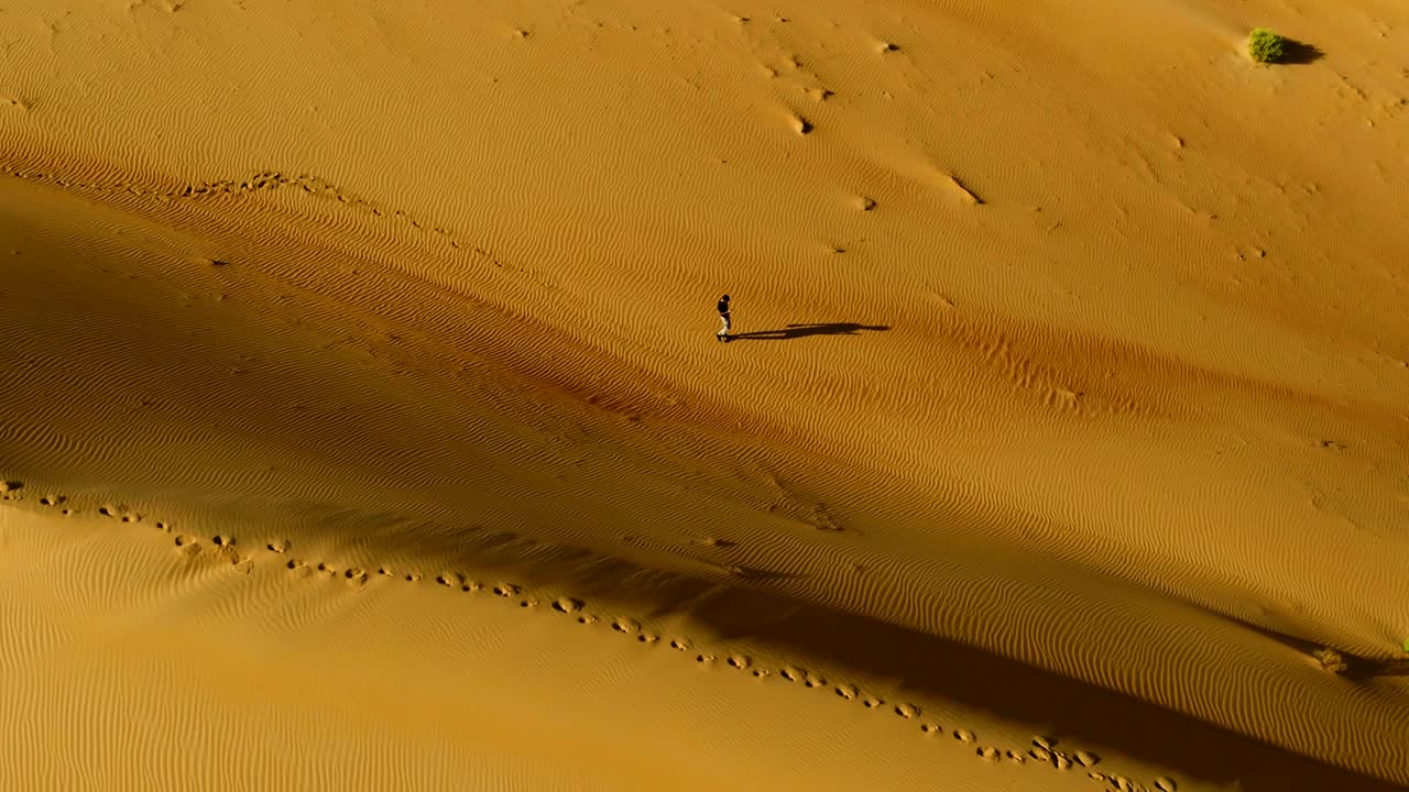 Aerial view above of a man walking alone in the dunes of Sharjah desert, U.A.E.