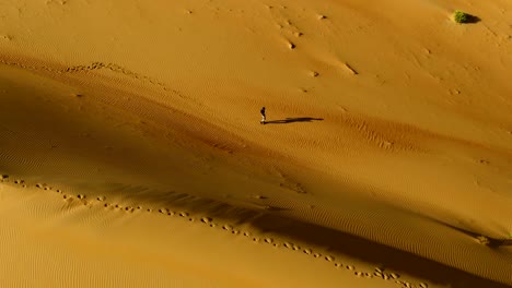 aerial view above of a man walking alone in the dunes of sharjah desert, u.a.e.