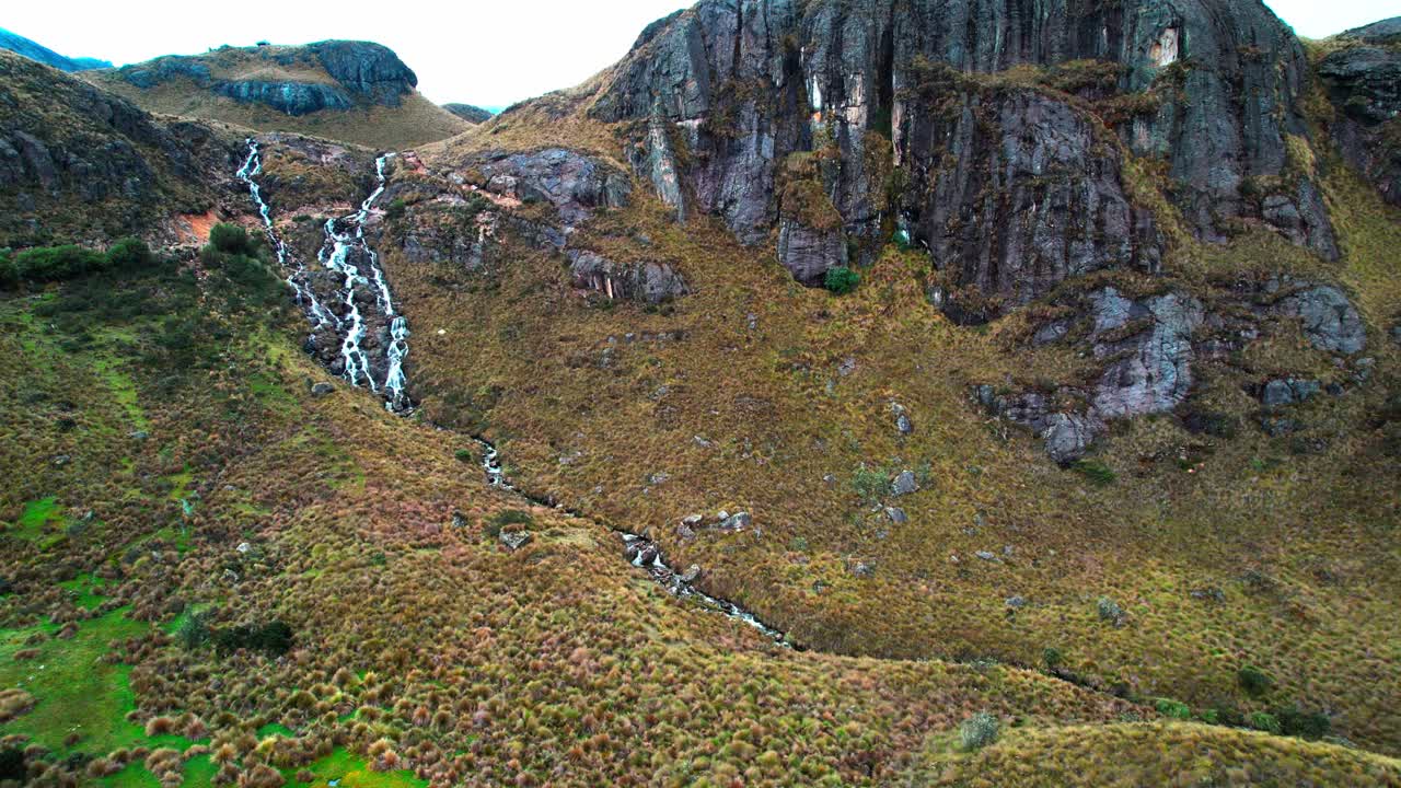 vuelo de un avión no tripulado con una toma cinematográfica de una cascada de uno de los parques más hermosos de ecuador con el sol brillando en las montañas alrededor