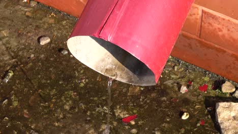 water is flowing from a red downspout