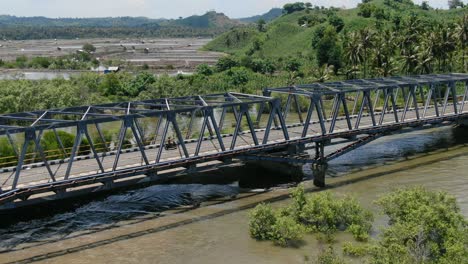 aerial view moving forward shot, a bridge connecting southern lombok, scenic view of the rice fields and palm trees