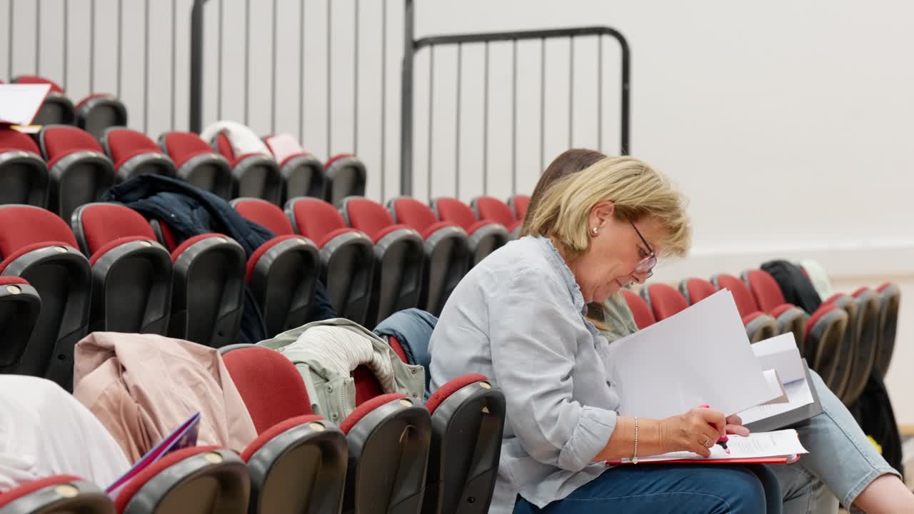 Mature students sitting together taking notes in lecture hall setting