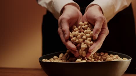 Hands scooping bowl full of tasty hazelnuts