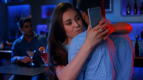 mujer chequeando su teléfono móvil mientras abraza a un hombre