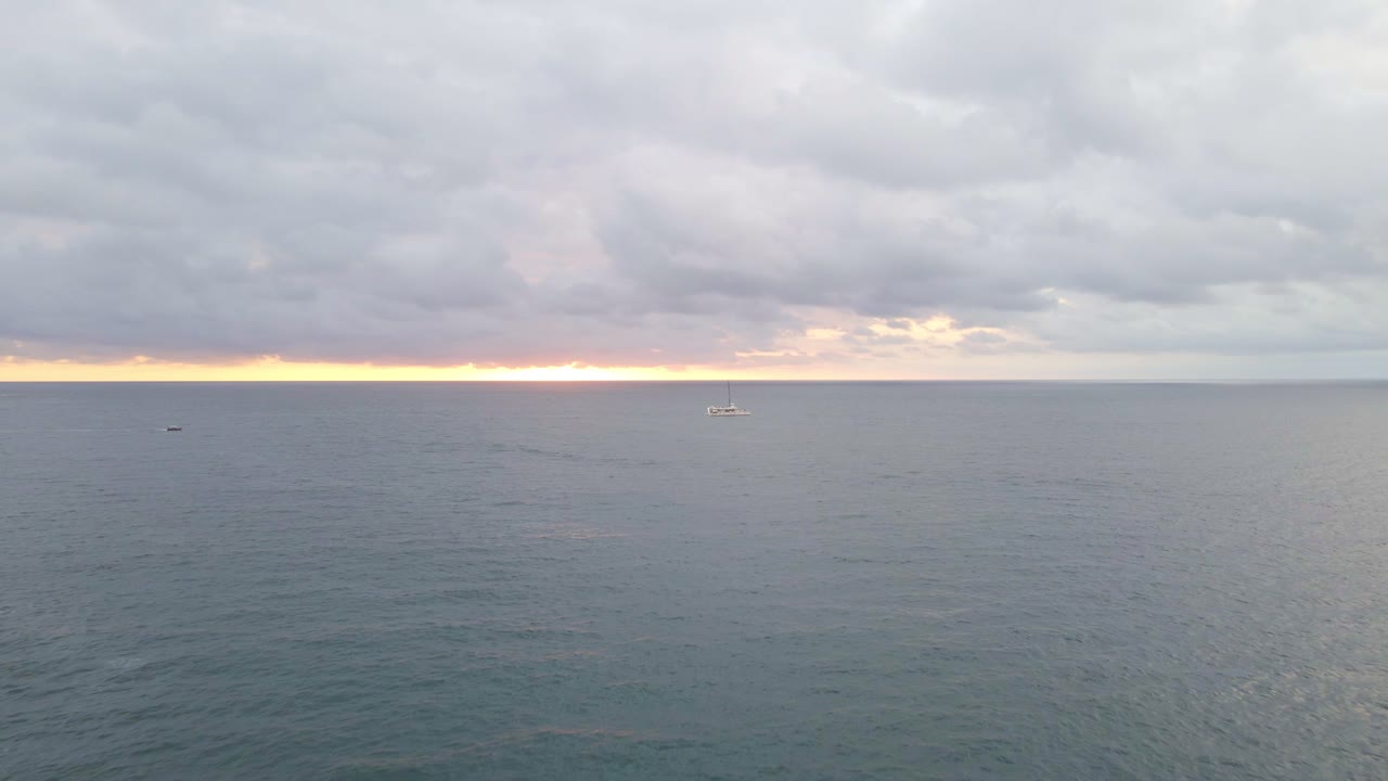 멋진 오렌지색 일몰과 배에서 멀리 바다 위로 드론 비행을 뒤로