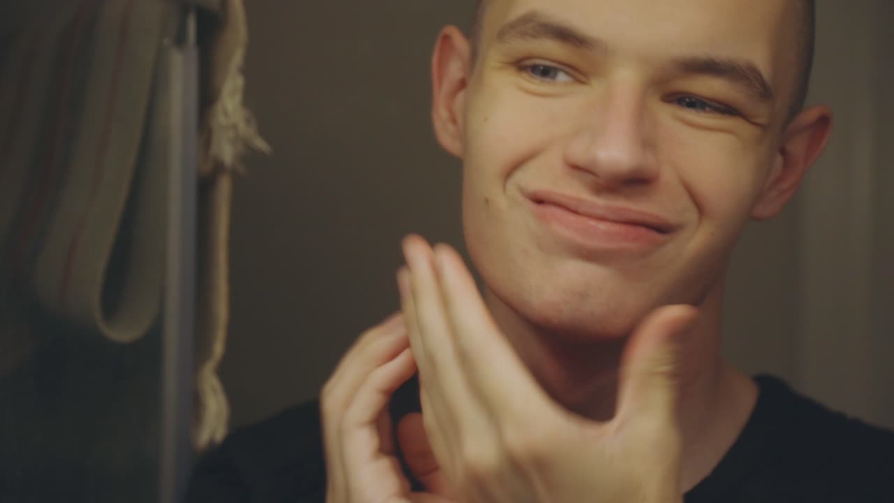 Caucasian Man Touching His Face After Shaving In Front Of A Mirror - close up