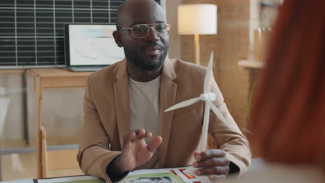 ingeniero afroamericano discutiendo la turbina de molino de viento con un colega