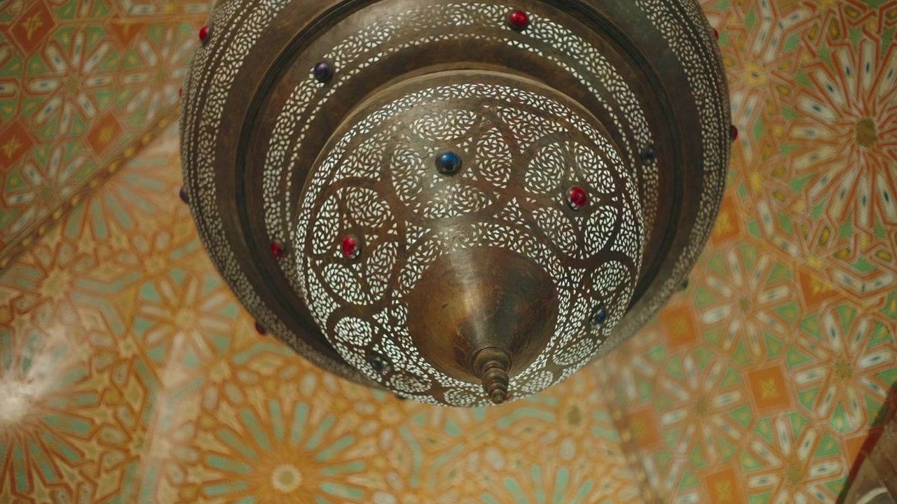 Detailed underside of traditional metal lantern with pierced pattern over zellige tile ceiling