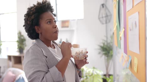 African-american-casual-businesswoman-eating-lunch-in-office,-slow-motion