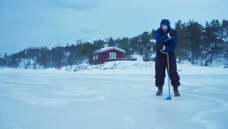 Der-Mann-Bohrt-Mit-Einem-Handbetriebenen-Bohrer-Ein-Loch-In-Den-Zugefrorenen-See-Zum-Eisfischen-In-Bessaker,-Provinz-Trondelag,-Norwegen-–-Statische-Aufnahme