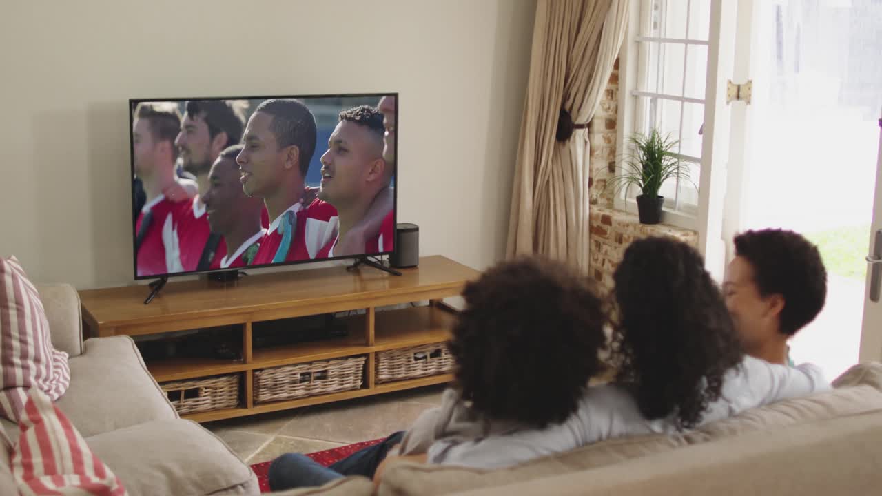 Famiglia felice seduta a casa insieme che guarda un evento sportivo in TV