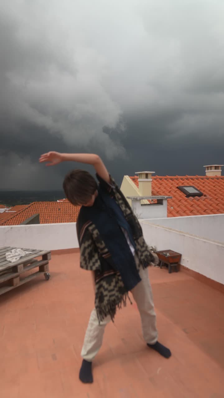 Bambino che balla su un tetto durante una tempesta