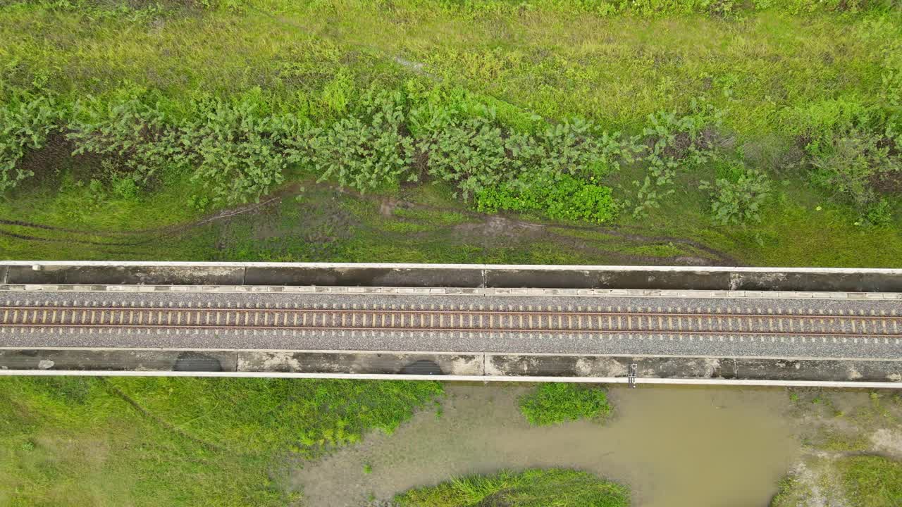 Ascending aerial footage of an elevated provincial railway in Saraburi, Thailand.