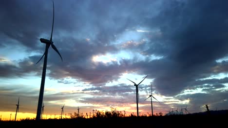 renewable sustainable wind turbines against dramatic sunset sky panning right