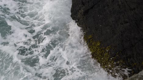 mossy rocks with crashing waves in newquay harbour, cornwall, england