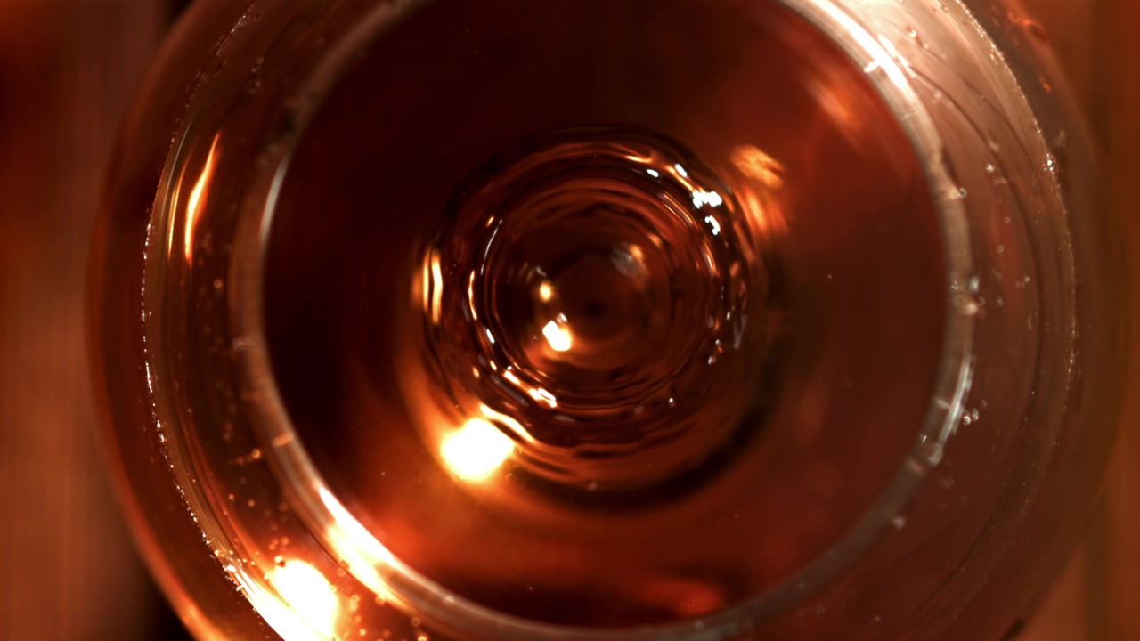 Goccia in slow motion che schizza nel whisky dorato in un bicchiere