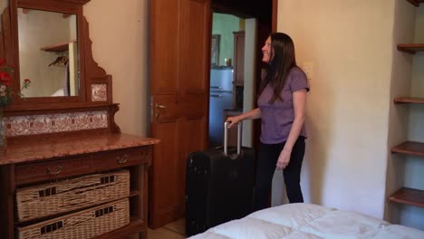 delighted female traveller with luggage arriving at rented apartment