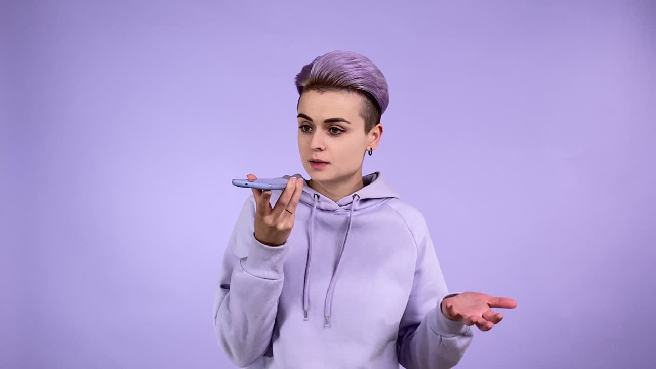 Young woman in purple using speakerphone, sending audio voice message