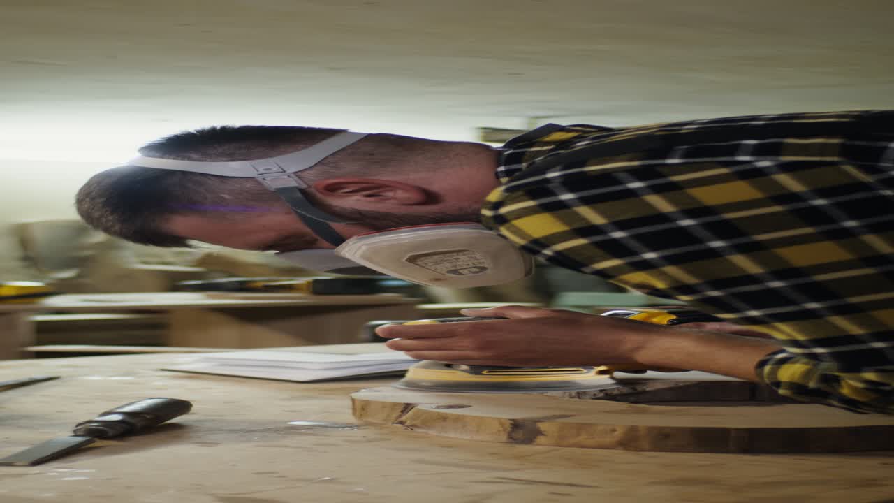 trabajador de la madera lijando una losa de madera en un taller