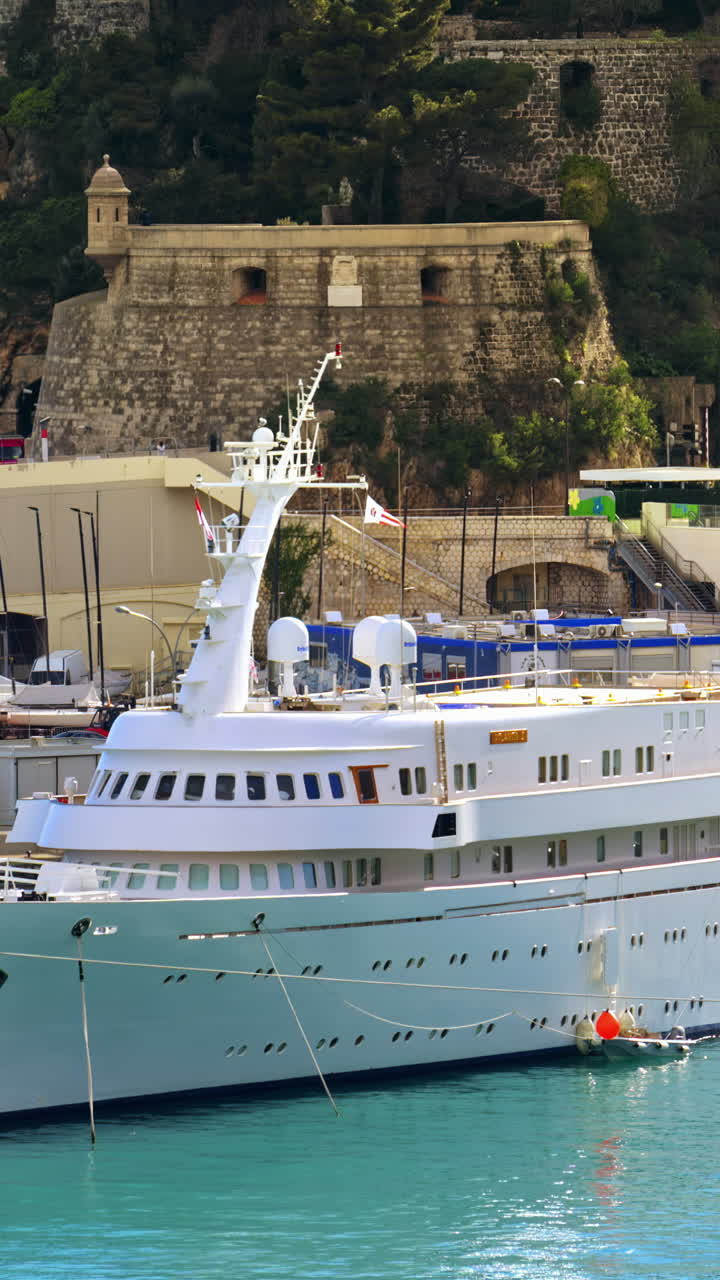 White yacht docked in the Monaco Marina in daylight. Vertical