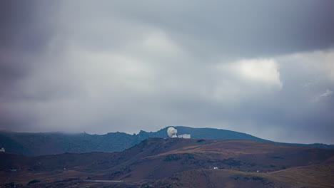 a time lapse shot of a dramatic sky and the clouds shadows travelling across the mountain peaks