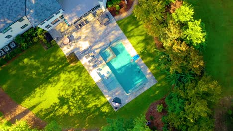 aerial drone shot slowly spinning while rising high above a mansion with bright blue pool in the backyard in atlanta, georgia