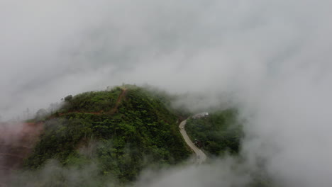 Cinematic-aerial-footage-of-a-tropical-rainforest-hill-and-a-street-in-fogg-in-the-Philippines,-Asia,-Drone