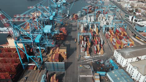 aerial dolly in of a container cargo ship docked in valparaiso sea port near cranes ready to be loaded, chile