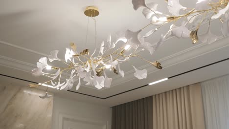 elegant floral chandelier with white petals and golden stems illuminates a luxurious interior.