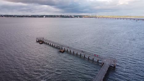 aerial footage of people walking a long a pier on the water in posadas, misiones, argentina