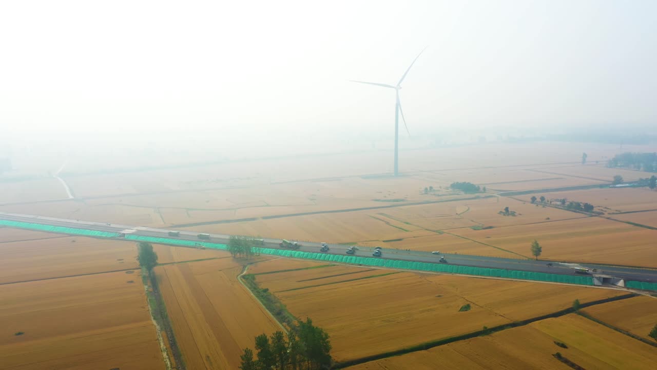 Aerial: pollution over a road construction site and a wind turbine during the day in Bozhou, Anhui province, China, pull out drone shot
