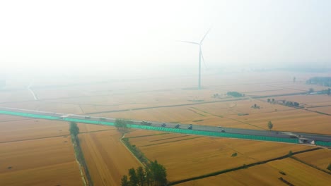 aerial: pollution over a road construction site and a wind turbine during the day in bozhou, anhui province, china, pull out drone shot