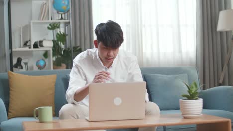 asian man being tired while using laptop computer in the living room