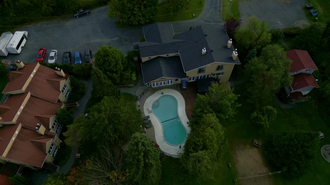 Smooth drone movement over lush green landscapes towards luxurious home with pool in Sutton, Quebec, breathtaking aerial view in nature and modern architecture.