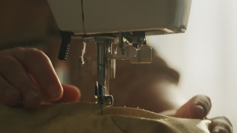 uma mulher costura roupa de cama numa máquina de costura, de perto.