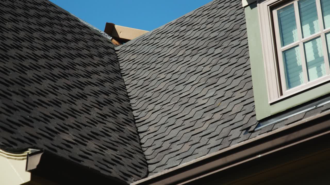 Close-up view of a house roof with dark grey asphalt shingles