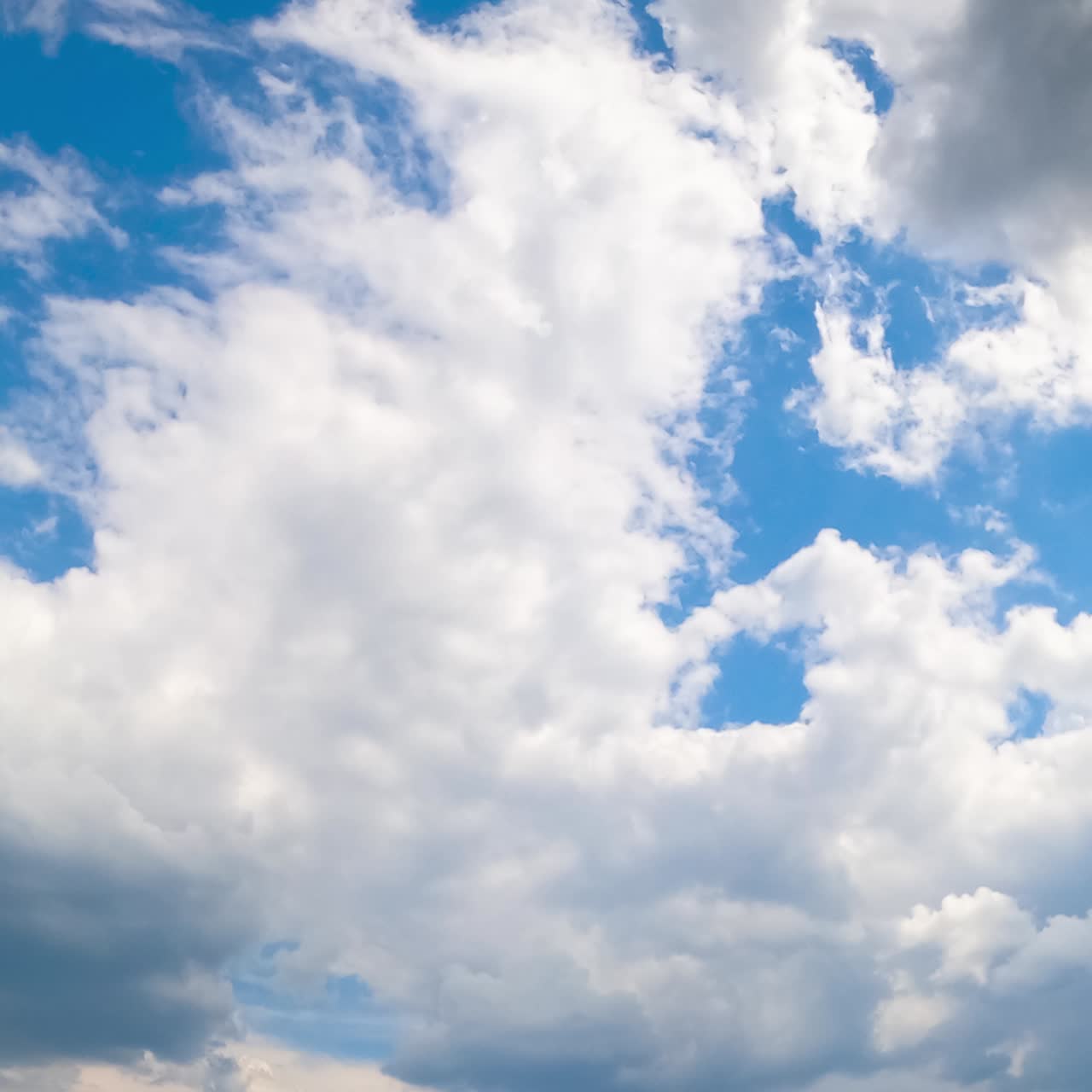 Soft light white clouds quickly floating by the azure skies. Soft clouds gathering into a big cloudscape. Low angle view timelapse