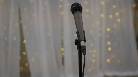 wedding day stock clip of mic microphone on stand with led bokeh lights in background and white backdrop ready for performer singer artist or toast speeches