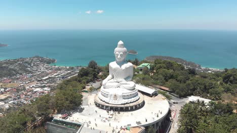 Vista-De-Paralaje-Del-Gran-Buda-De-Phuket-Contra-El-Paisaje-Del-Océano-Azul---Toma-Panorámica-Aérea-De-órbita-Amplia