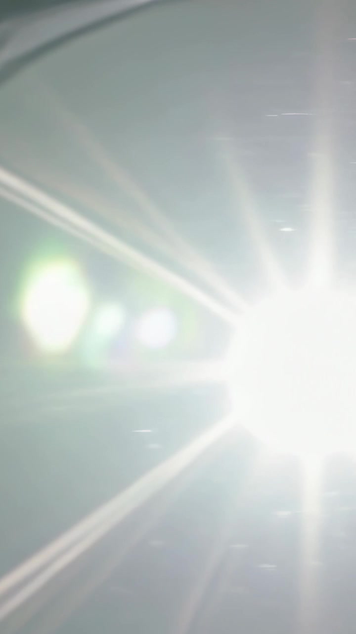 Vertical video: Entering bright light causing glossy rim scattering starburst flare closeup