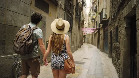 4k video footage of an unrecognisable couple holding hands and walking through the streets of barcelona