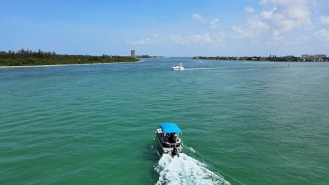 flying low over an ocean bay as boats pass below the camera