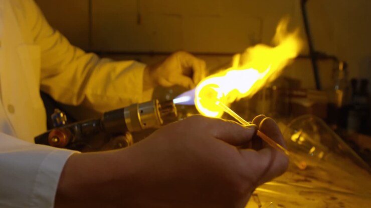 Mid section of male worker blowing glass in glass factory 4k