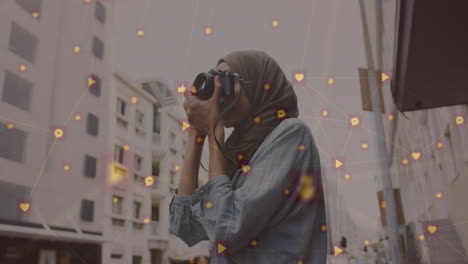 animation of network of connected icons and woman wearing hijab taking photos in street