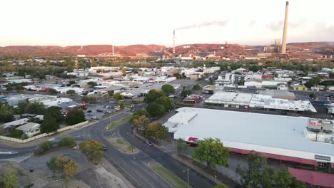 Drone-aerial-of-Mount-Isa-town-and-mining-hub-during-sunrise-over-cars-driving-on-road