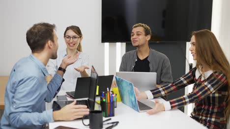 Glückliche-Kreative-Geschäftsleute-Mit-Laptops-Im-Büro,-Die-Gemeinsam-über-Projekte-Diskutieren