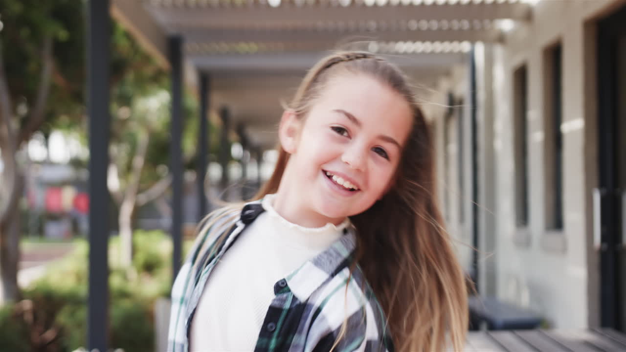 Girl making peace signs outdoors during school break, smiling brightly