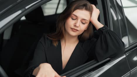 a beautiful adult girl in the driver's seat hugs a new car