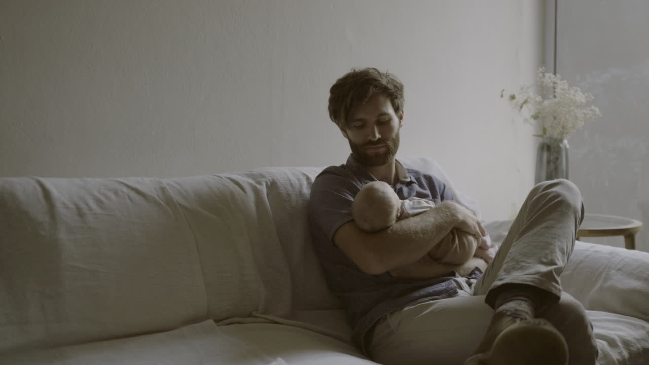 Pai segurando bebê recém-nascido no sofá